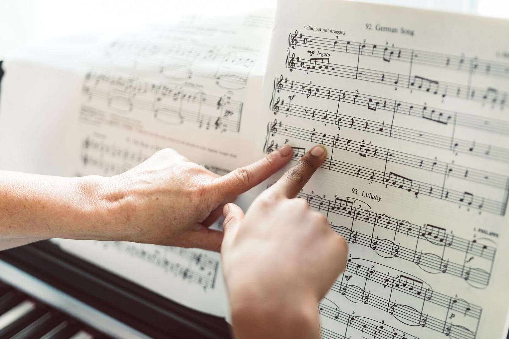 teacher and student pointing at sheet music for the piano