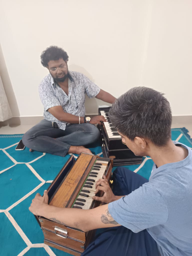 Teacher and a student playing the harmonium during classes