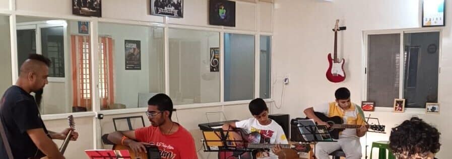 Eric Rodrigues teaching guitar at The First Chord Music and Art School, with students all around
